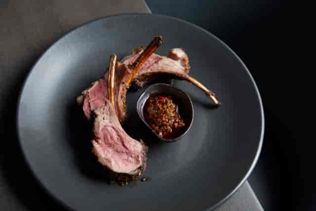 Semi-private dining room with elegant lamb chops, ideal for corporate dinners and upscale events.