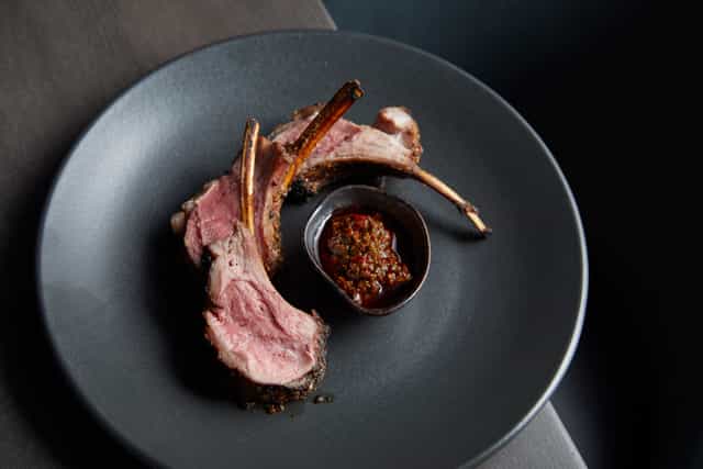 Semi-private dining room with elegant lamb chops, ideal for corporate dinners and upscale events.