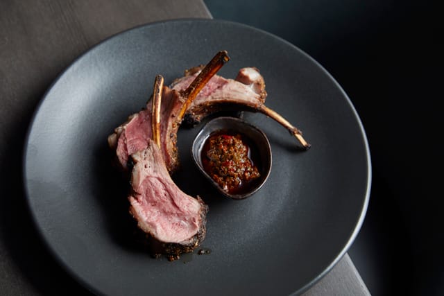 Semi-private dining room with elegant lamb chops, ideal for corporate dinners and upscale events.