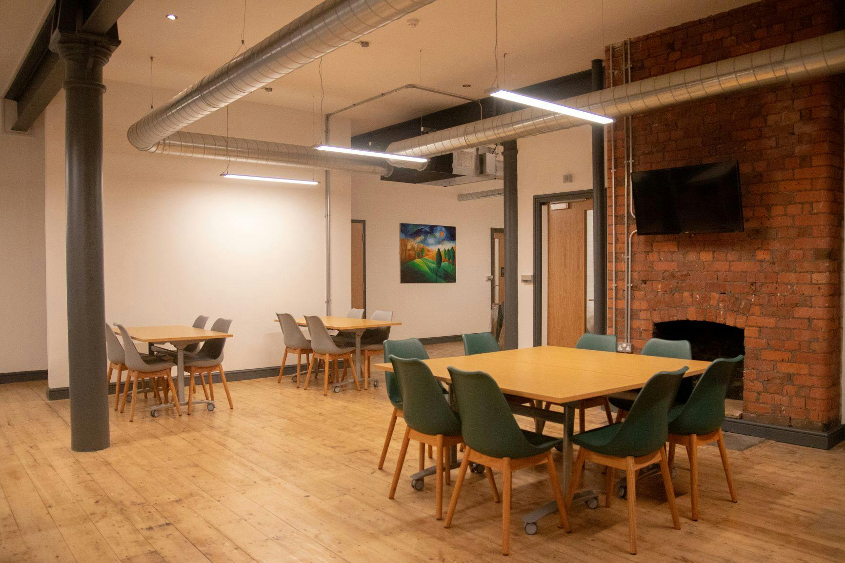 Versatile meeting space with wooden flooring, ideal for workshops and small events.