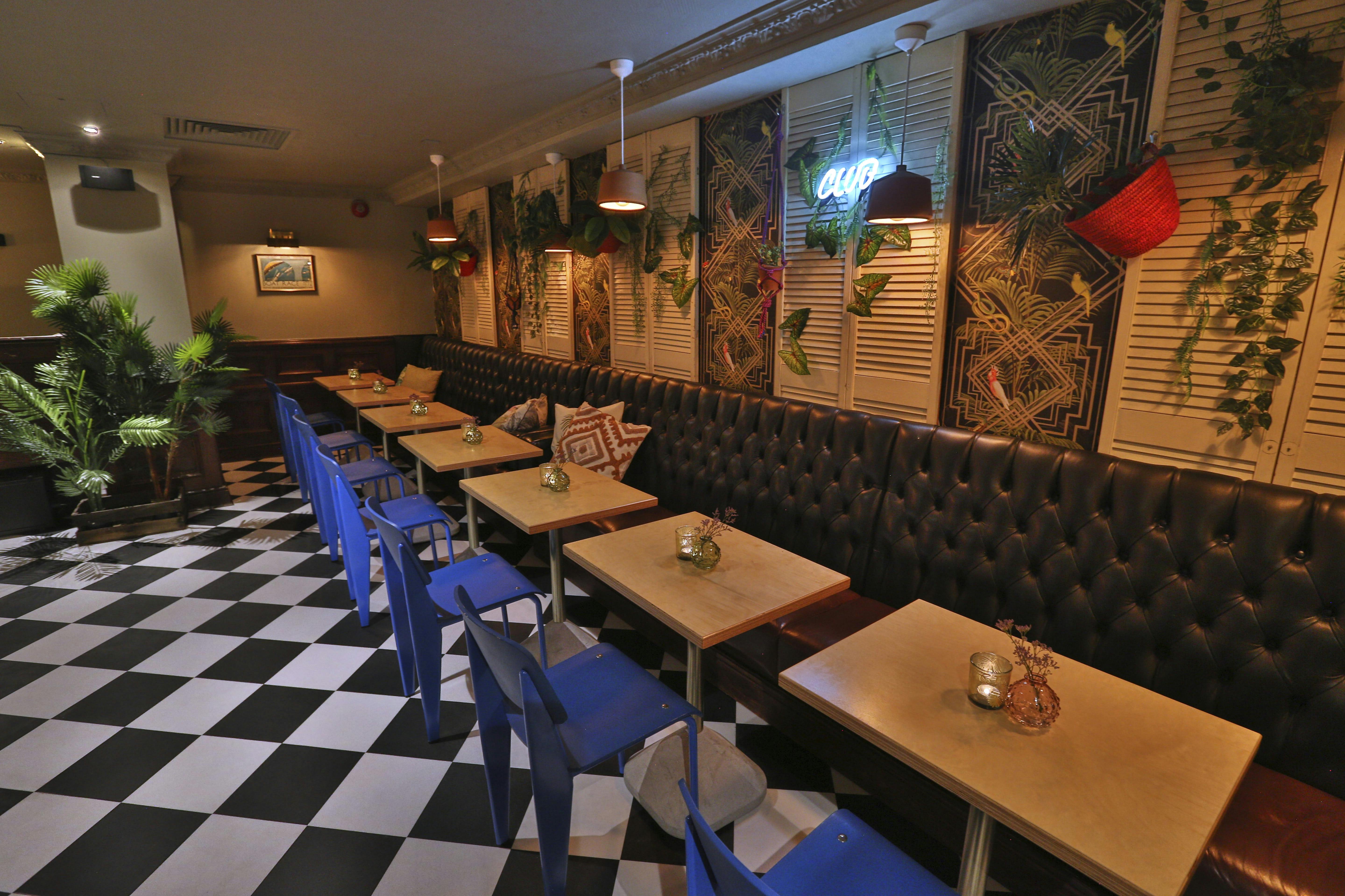 Stylish bar and restaurant event space with checkered floor and cozy seating.