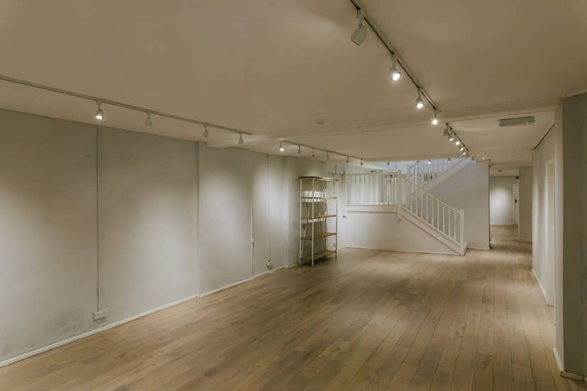 Versatile basement event space with wooden flooring, ideal for meetings and workshops.