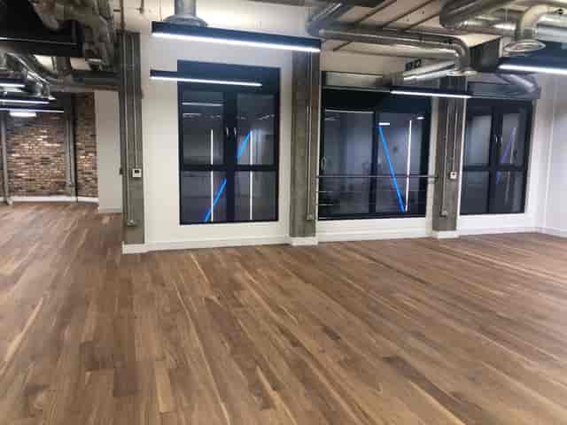 Versatile event space with large windows and wooden floor for meetings and gatherings.