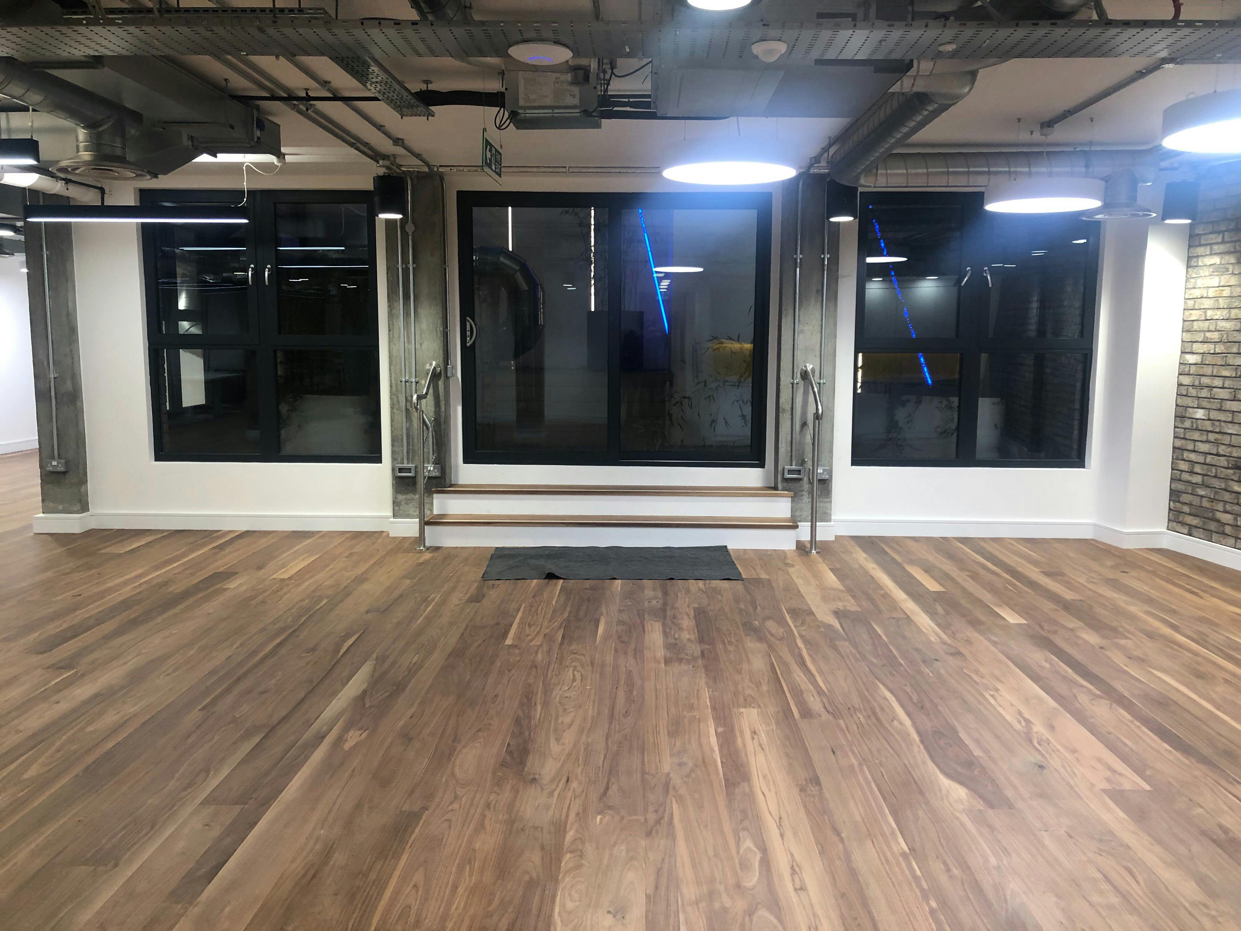 Versatile event space with large windows and wooden flooring for meetings and gatherings.