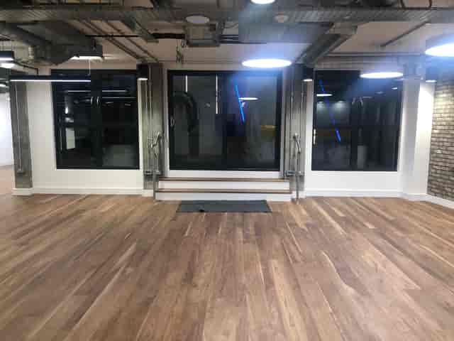 Versatile event space with large windows and wooden flooring for meetings and gatherings.