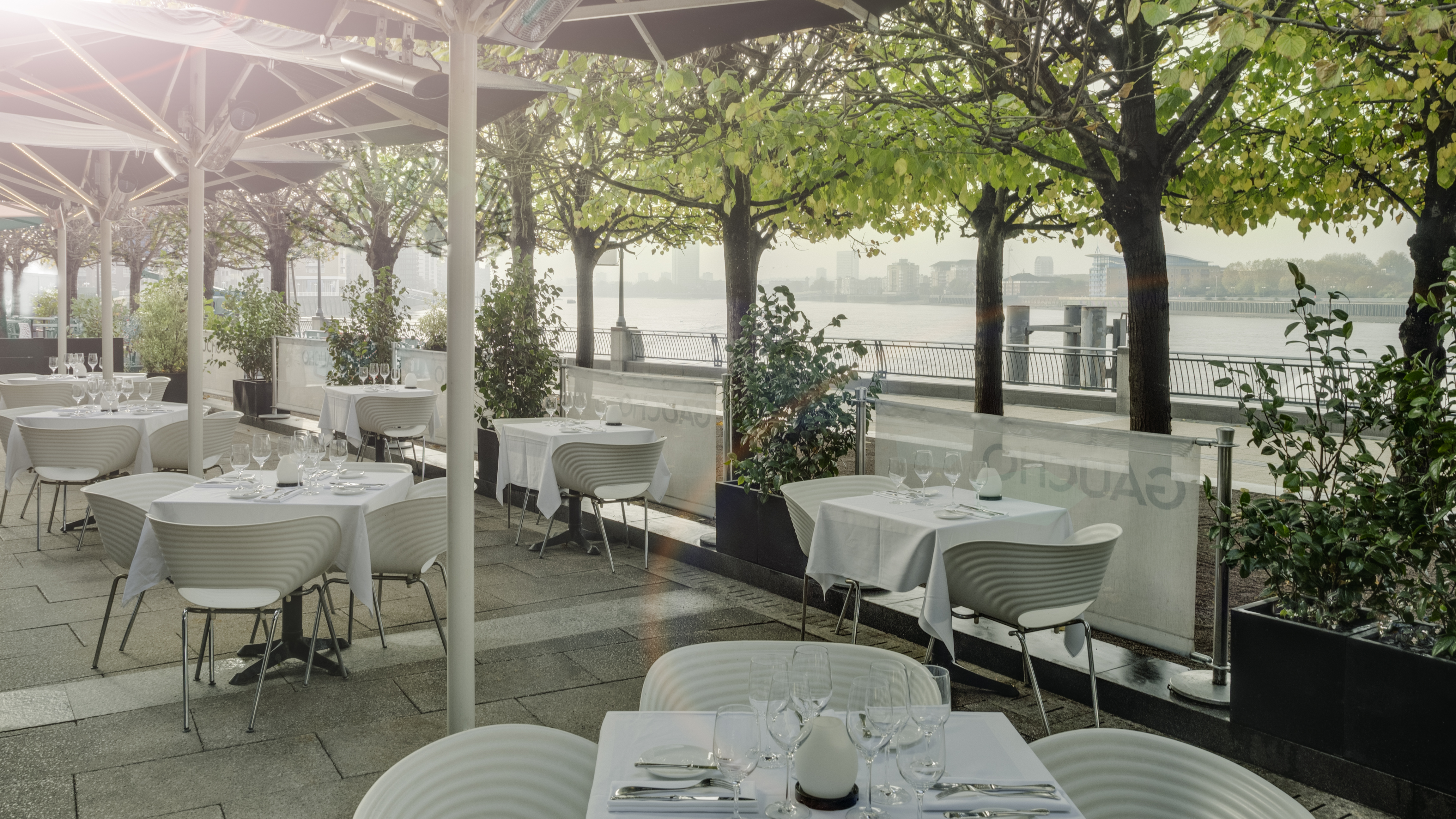 Outdoor dining venue at Gaucho Canary Wharf with elegant tables and waterfront view.