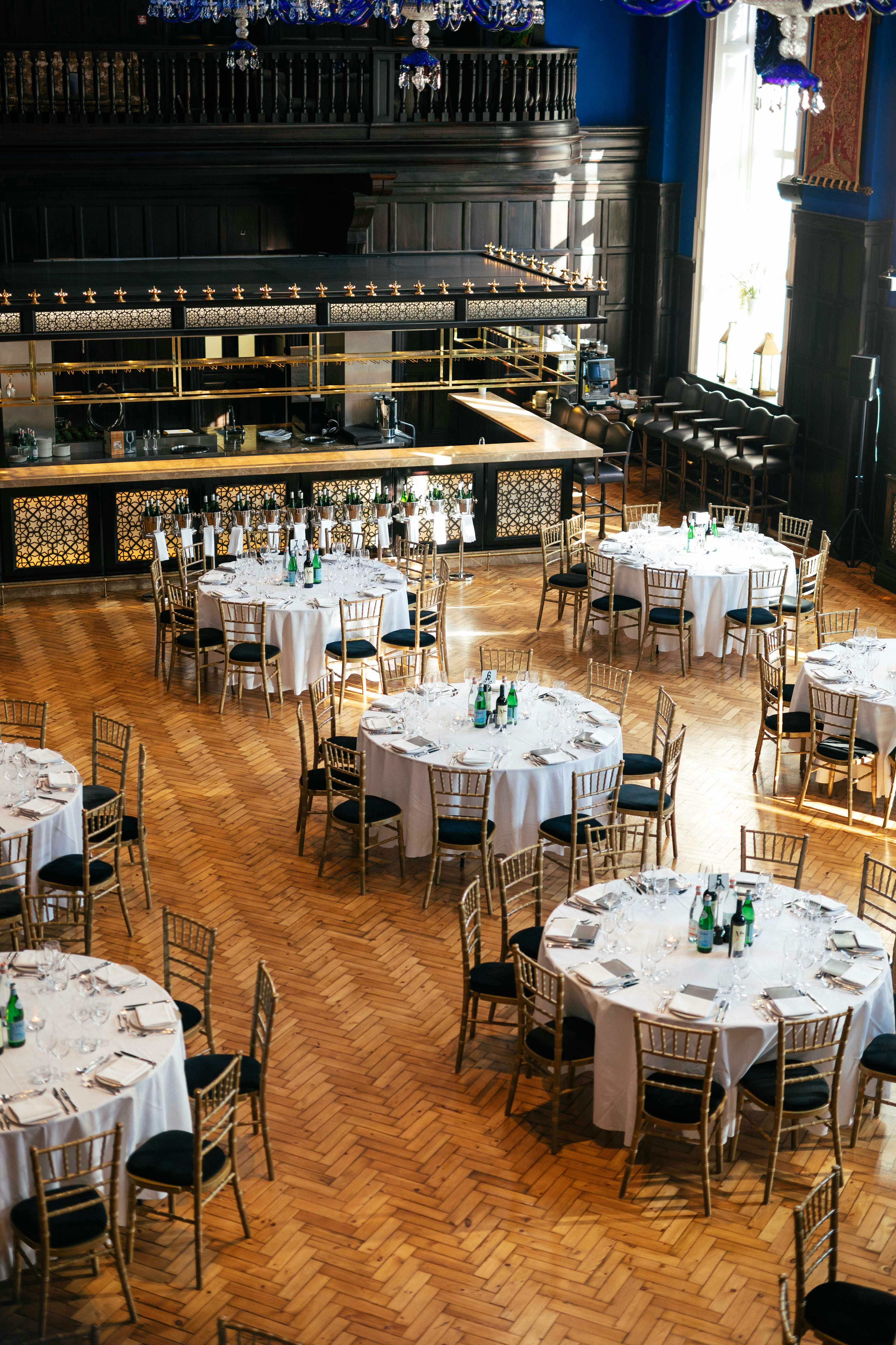 Elegant event space with round tables and gold chairs at The LaLiT London.