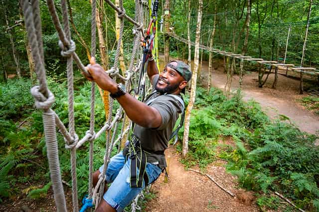 Individual on ropes course at Go Ape - Black Park, ideal for team-building events.