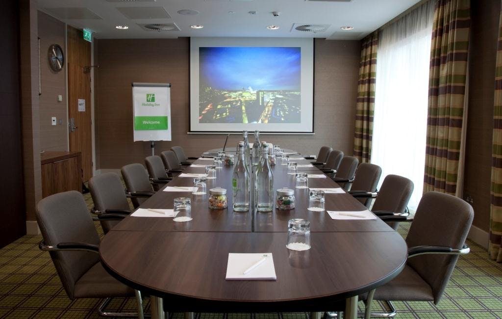 Meeting room with oval table at Holiday Inn London Stratford City for corporate events.