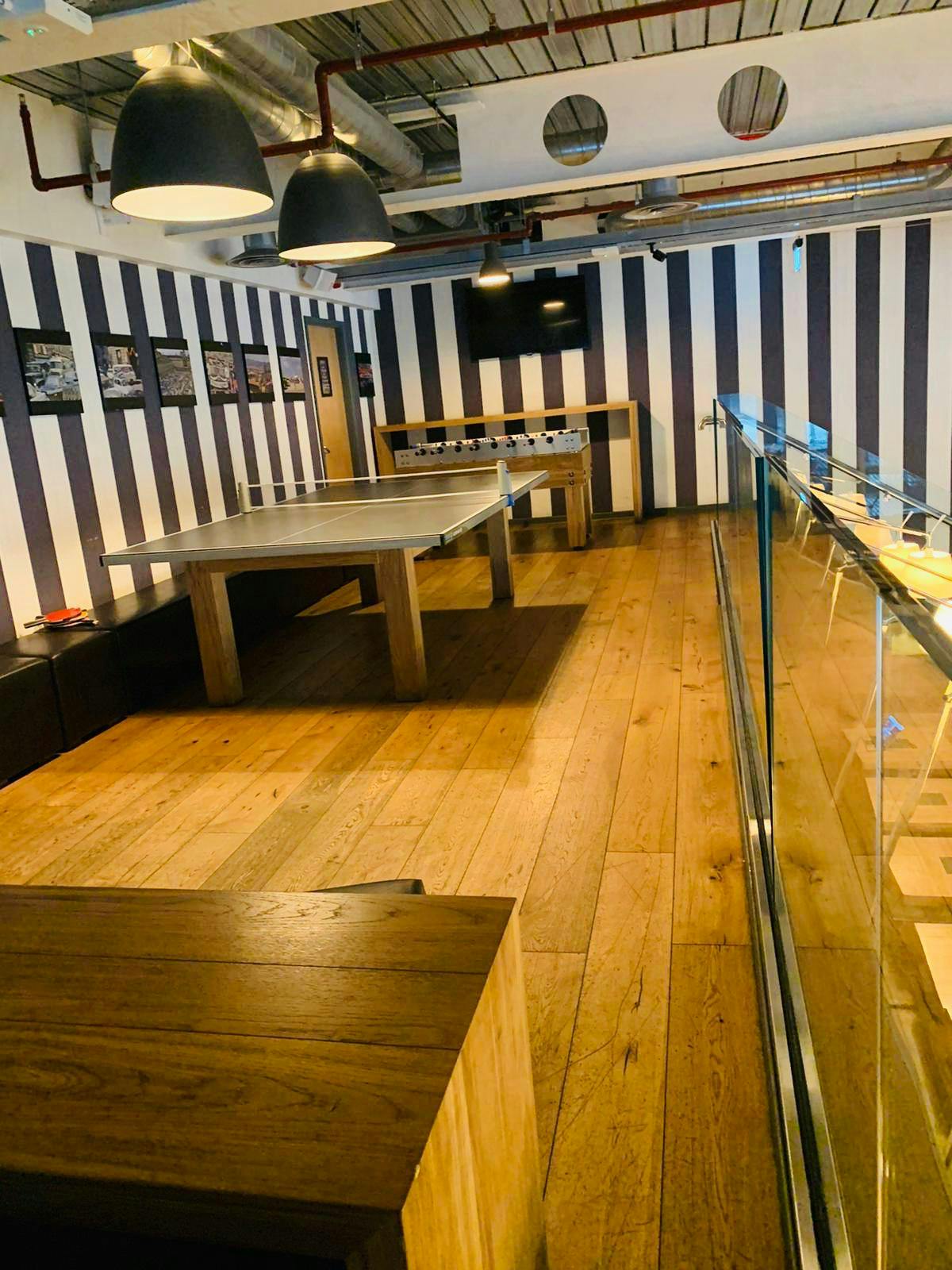 Modern meeting space with wooden floor and foosball table for team-building events.