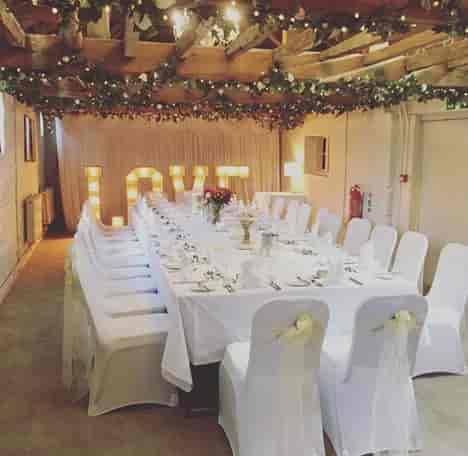 Elegant wedding banquet setup at The Surrey Barns with floral centerpieces and "LOVE" lights.