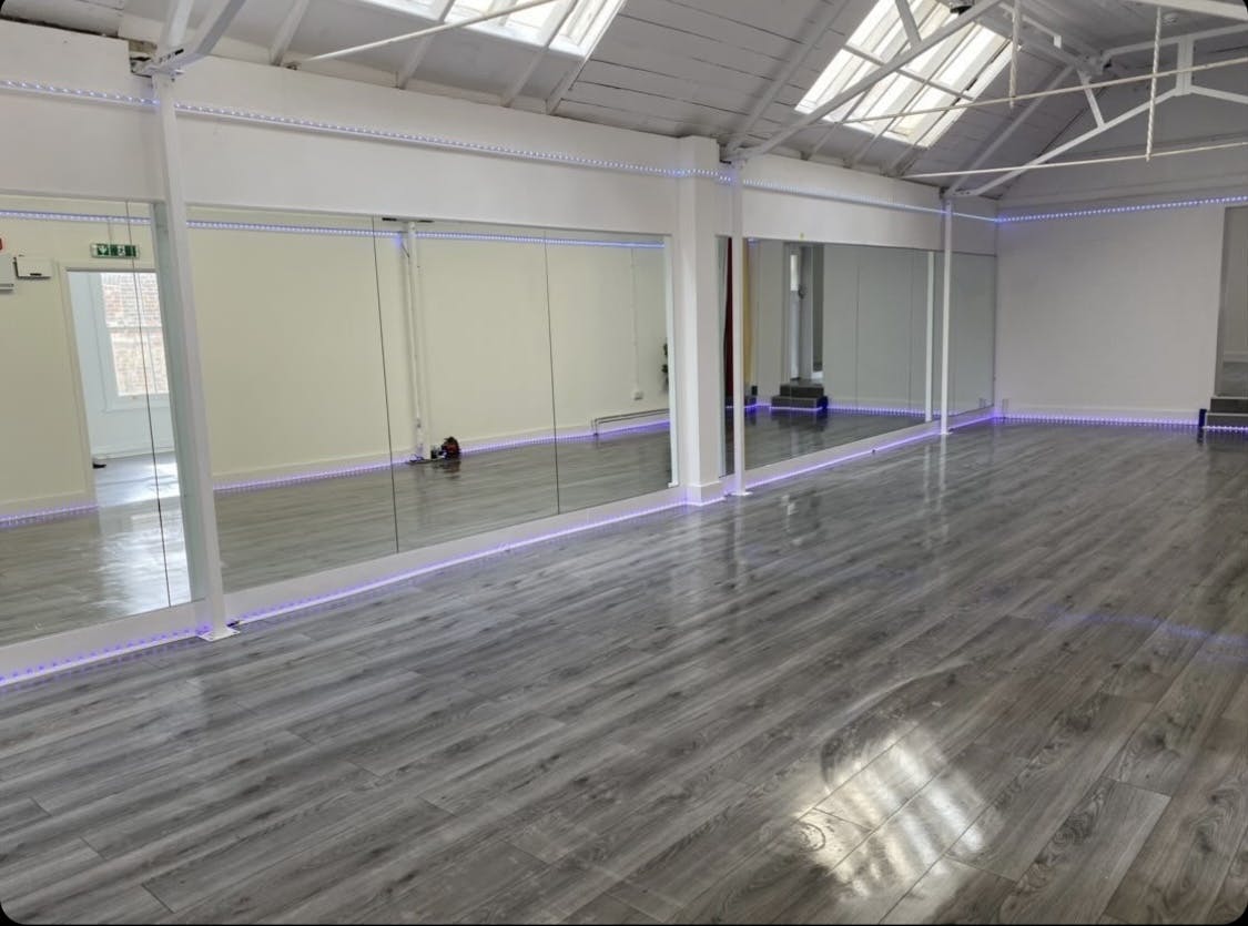 Versatile event space with polished flooring and mirrors for workshops and fitness classes.