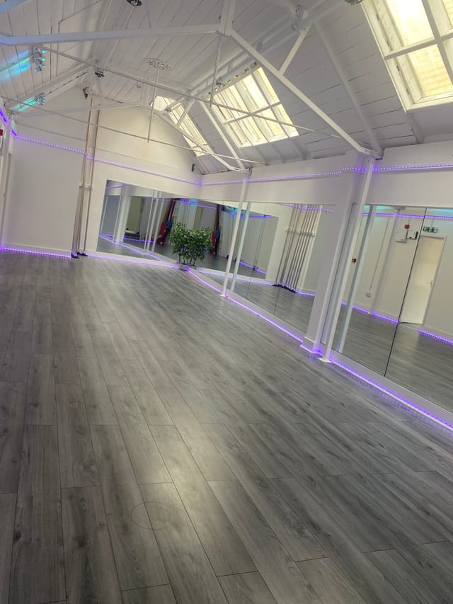 Versatile event space with modern flooring and mirrors, perfect for workshops and fitness classes.