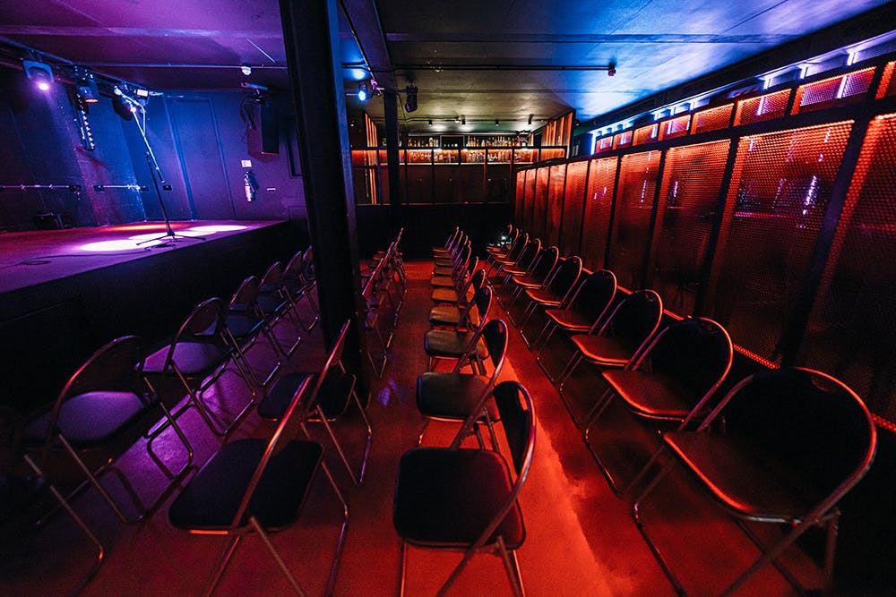 Intimate event space with black chairs and stage at Peckham Audio, perfect for performances.