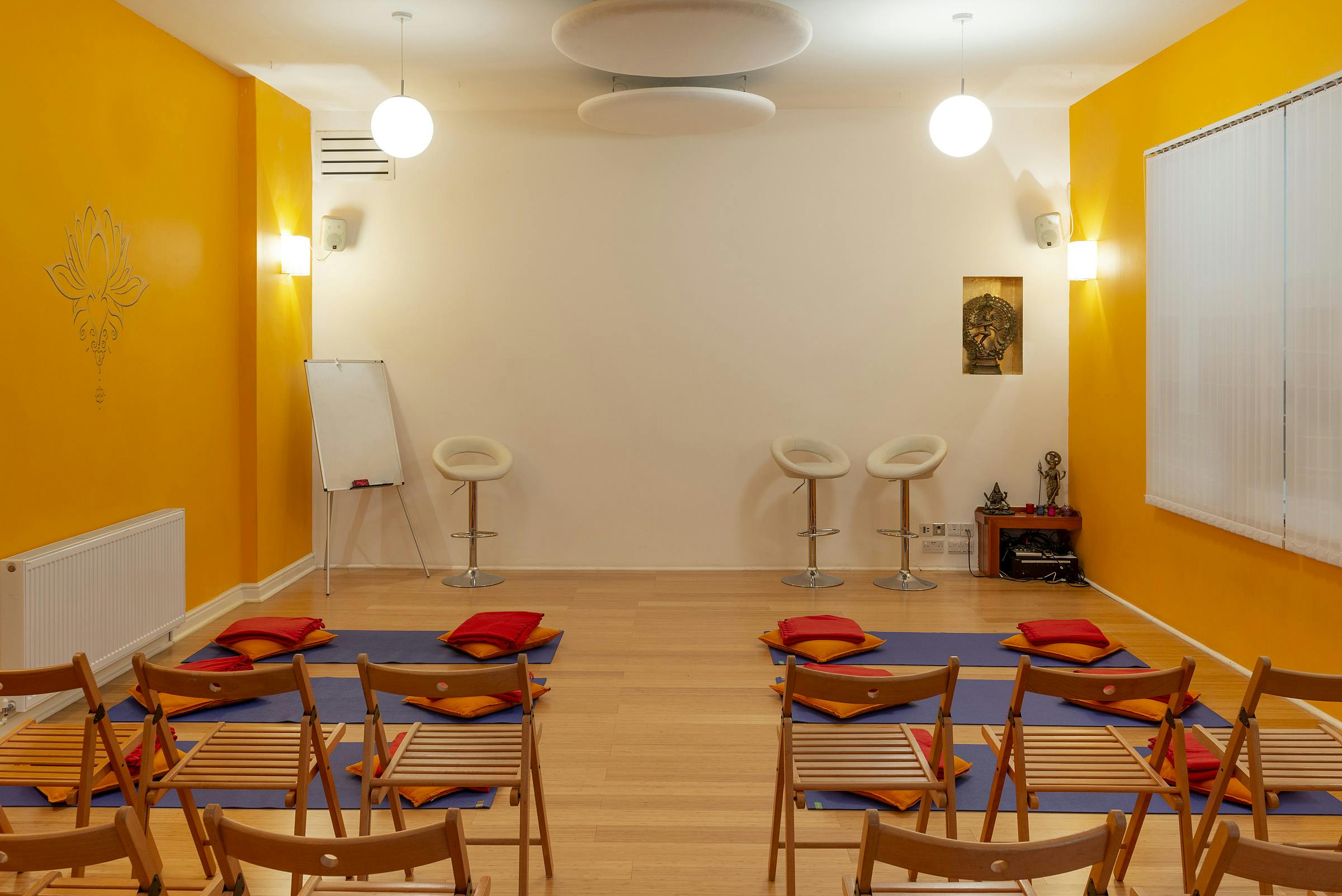 Shiva Studio at Tara Yoga Centre: cozy event space with vibrant yellow walls for workshops.