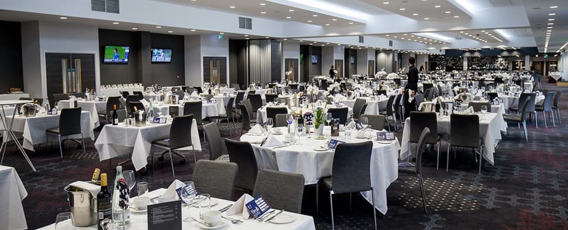 Formal event space at Ashton Gate Stadium with elegant tables and ambient lighting.