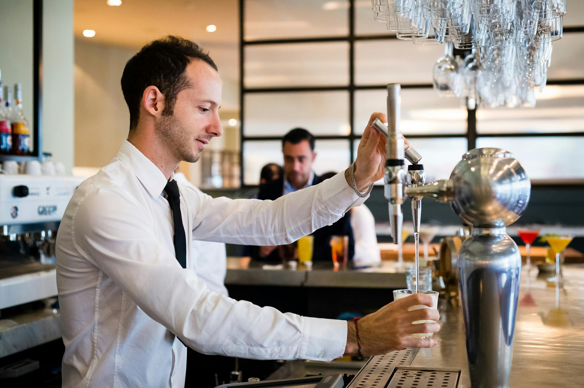 Bartender pouring drink at TOZI Restaurant & Bar, perfect for networking events.