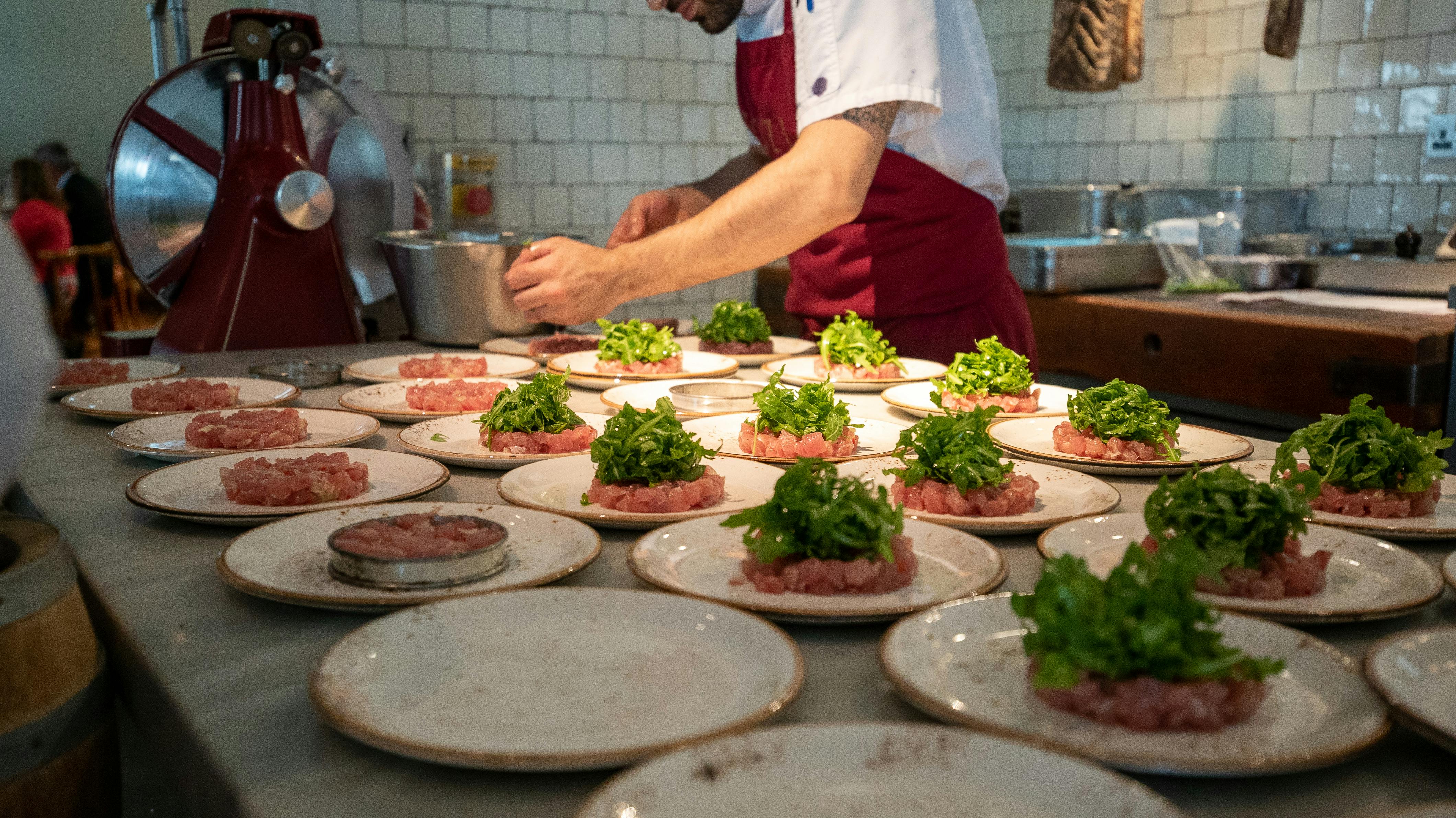 Culinary expert plating dishes at TOZI Restaurant for exclusive event catering.