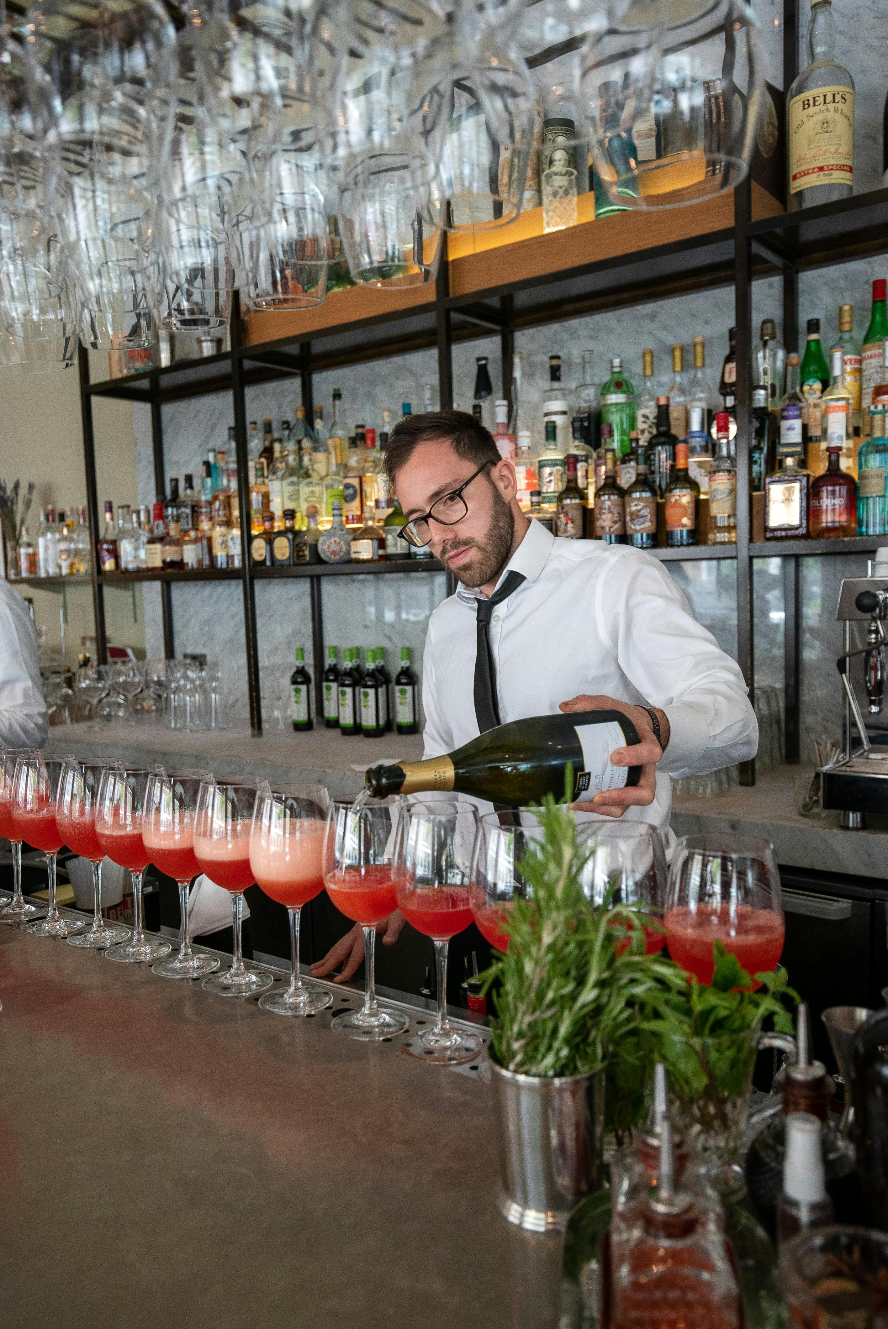 Bartender pouring champagne at TOZI Restaurant & Bar for upscale event hire.