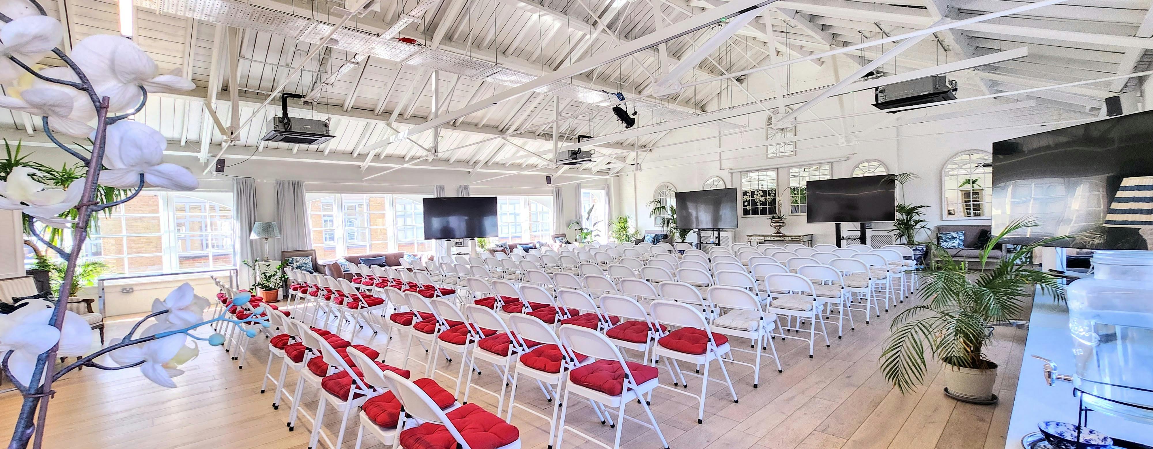 Event space with white chairs and red cushions for conferences and seminars.