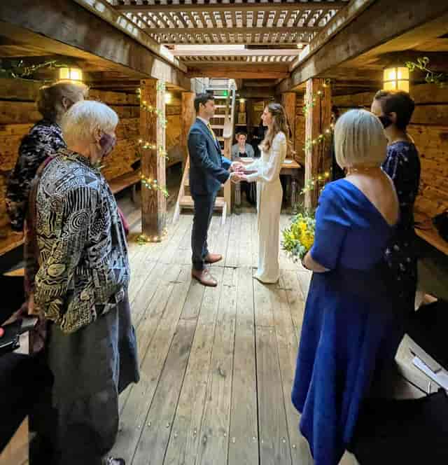 Intimate wedding ceremony in rustic wooden venue, warm lighting, unique event space.