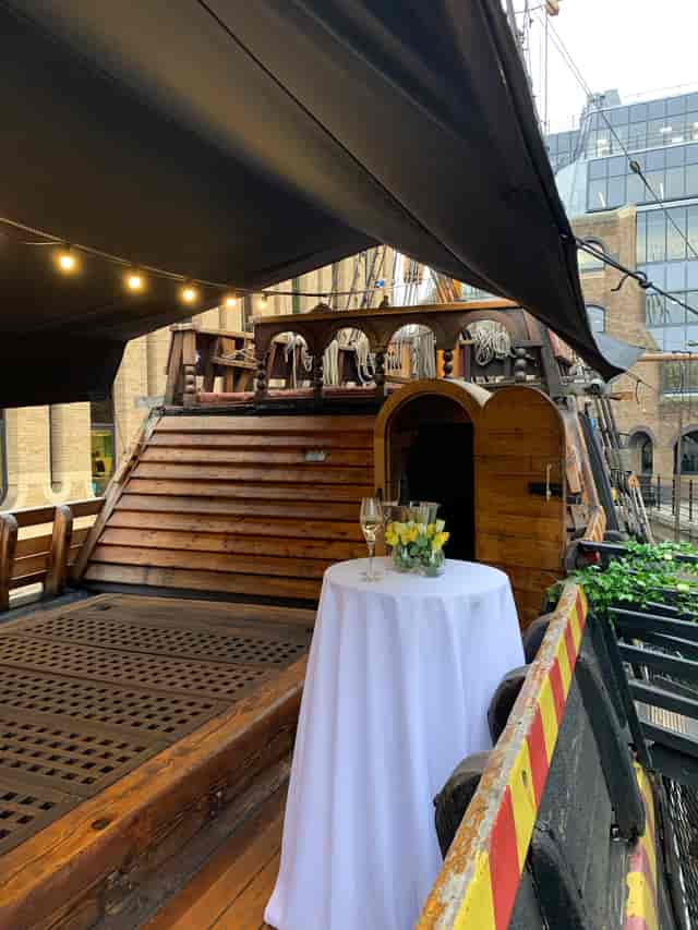 Whole Venue on The Golden Hinde, rustic ship event space with flowers and champagne.