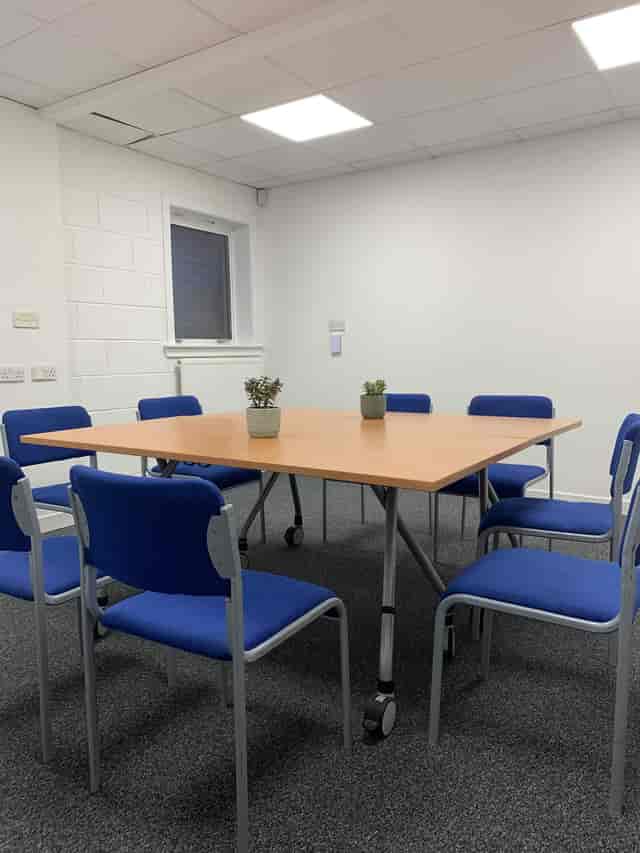 Auditorium in C7 Conference Centre with square table and blue chairs for meetings.