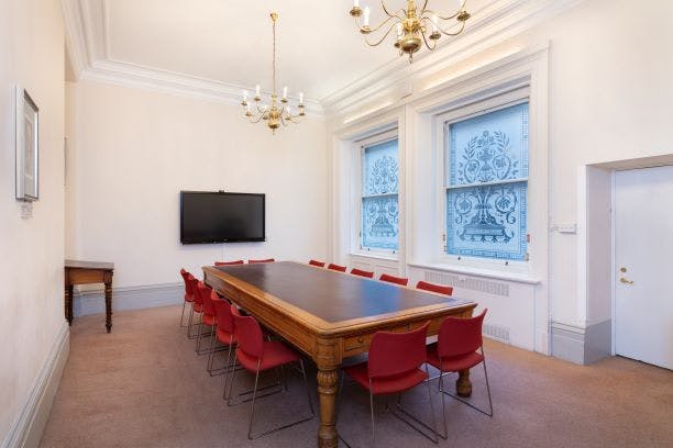 Arthur Holmes Room with wooden table, red chairs, ideal for meetings and presentations.