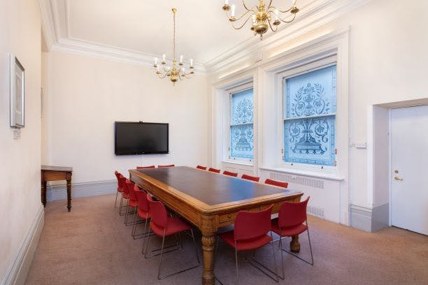 Arthur Holmes Room with wooden table and red chairs, perfect for meetings and presentations.