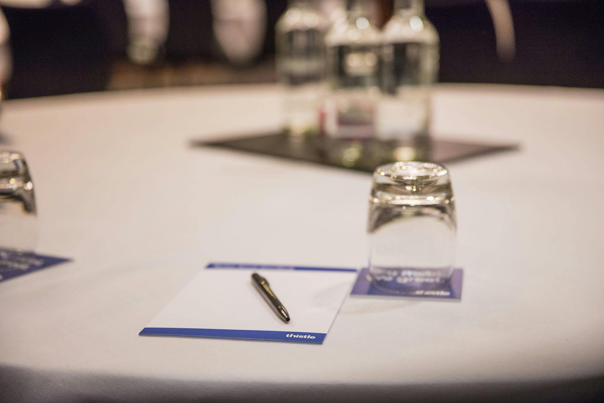 Meeting setup in Thistle Kensington Gardens with round table, notepads, and water bottles.