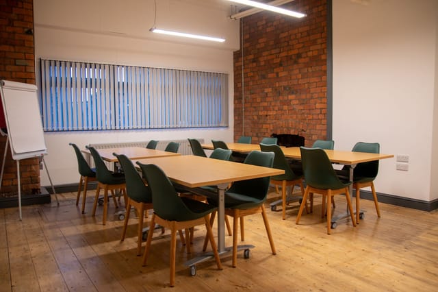 Versatile meeting space with wooden floors, ideal for workshops and brainstorming sessions.