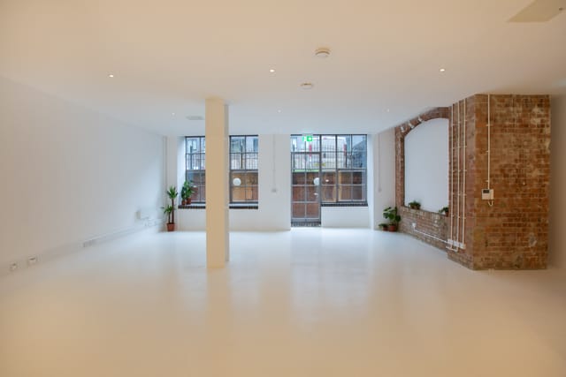 Versatile event space with natural light and exposed brick, ideal for meetings and workshops.