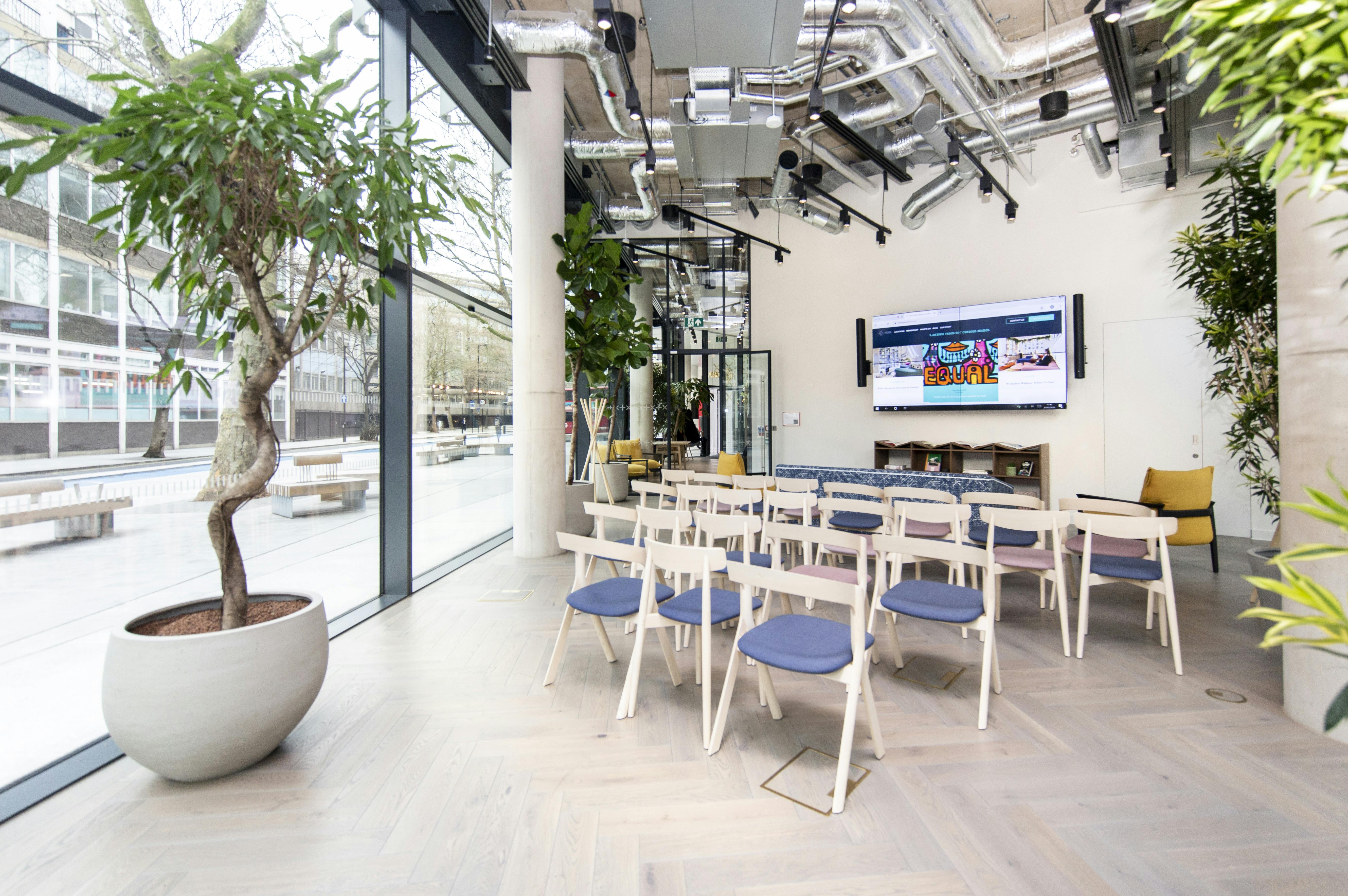 Modern event space in FORA-Southwark, featuring a large screen and greenery for workshops.