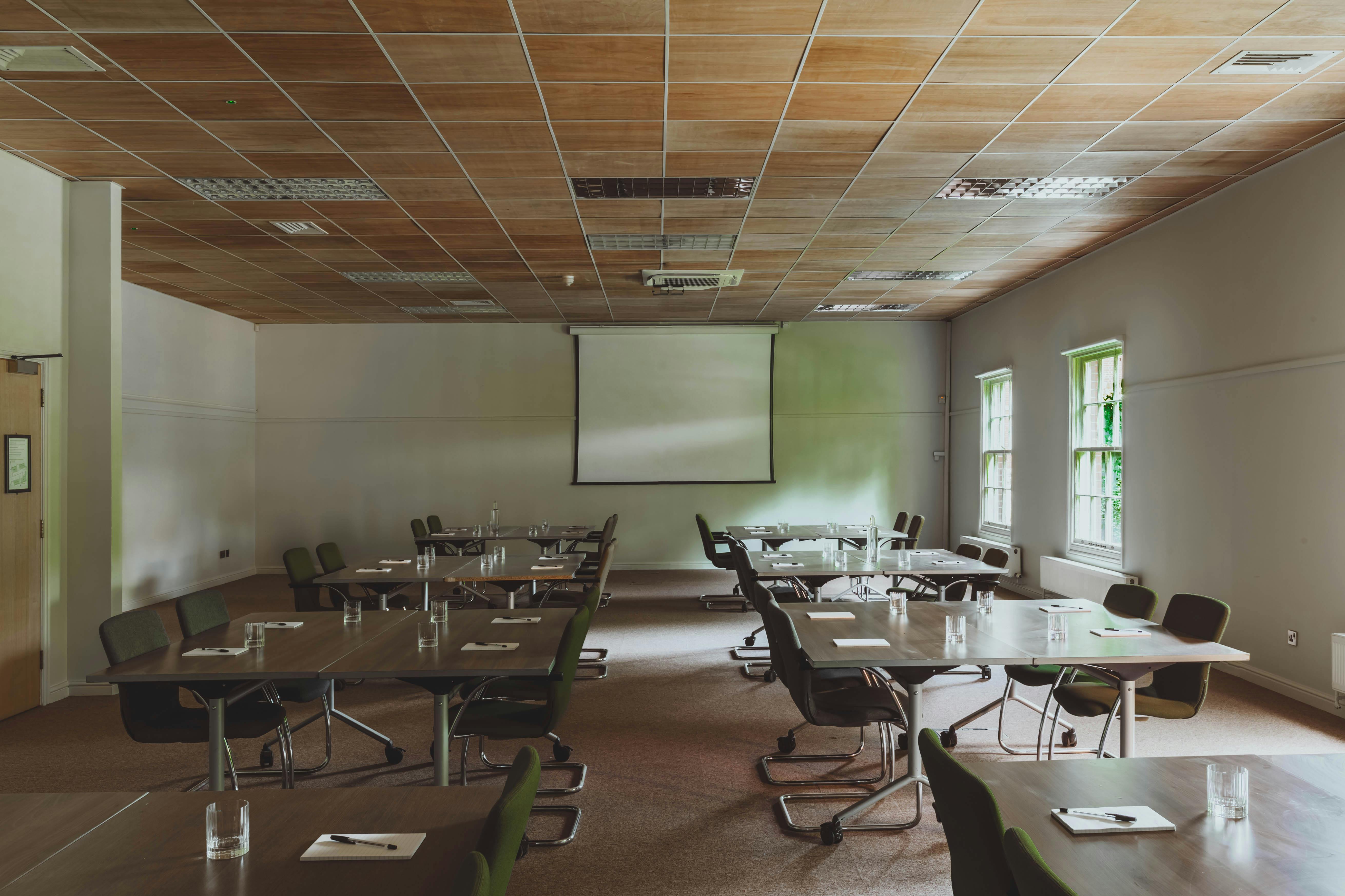 Versatile meeting room with tables, natural light, ideal for workshops and team meetings.