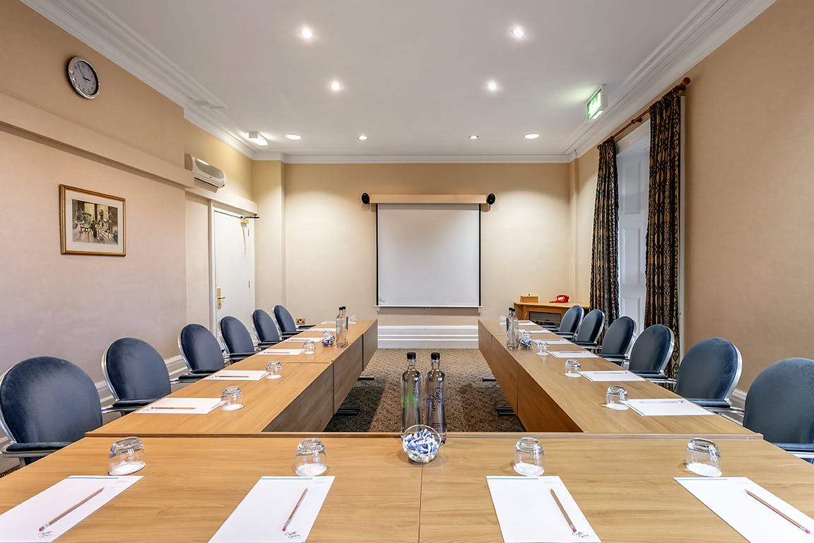 Garden Room at Castle Green Hotel, ideal for meetings with a long table and projector.