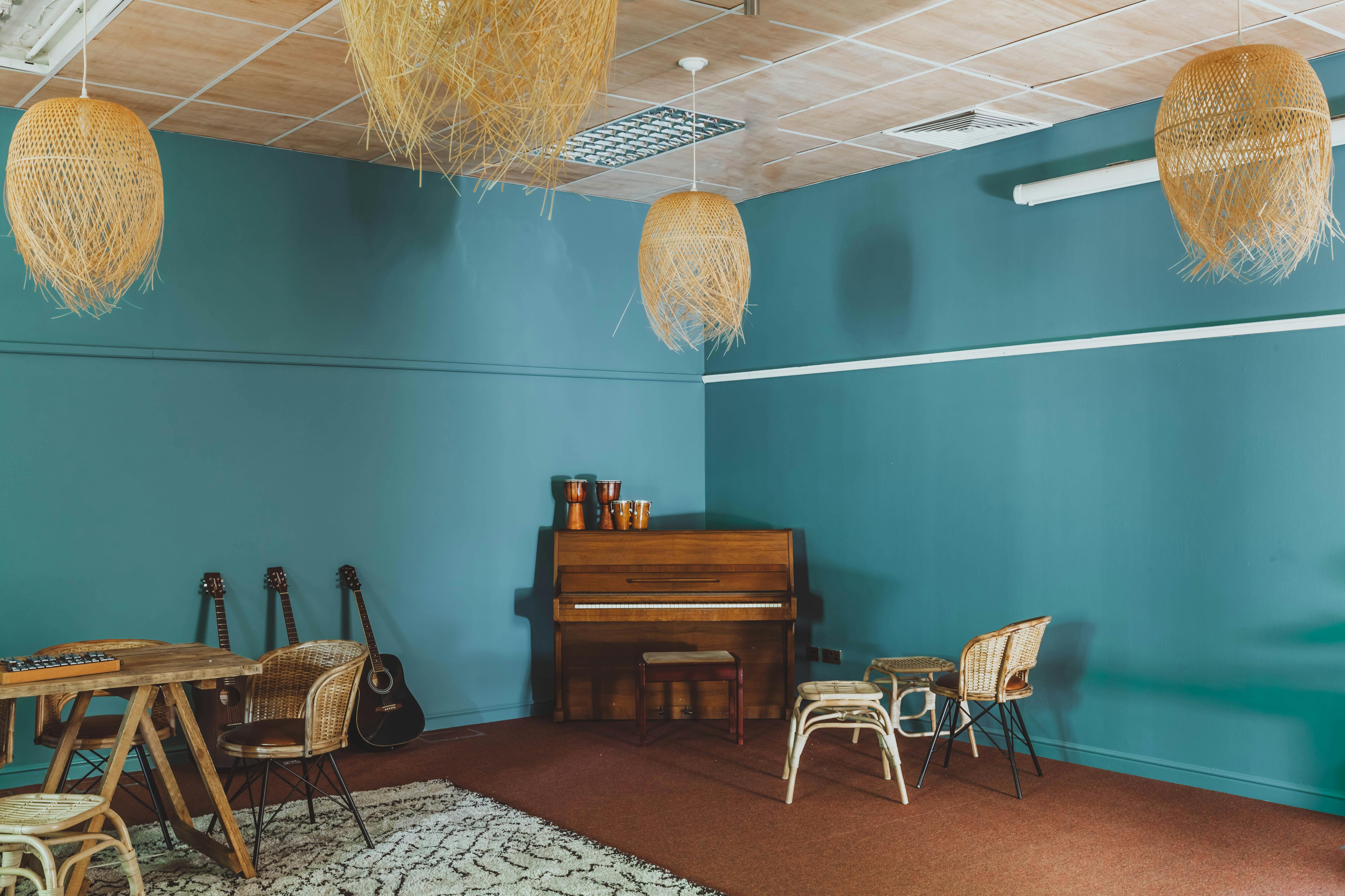 Cozy music room with teal walls, ideal for intimate gatherings and workshops.