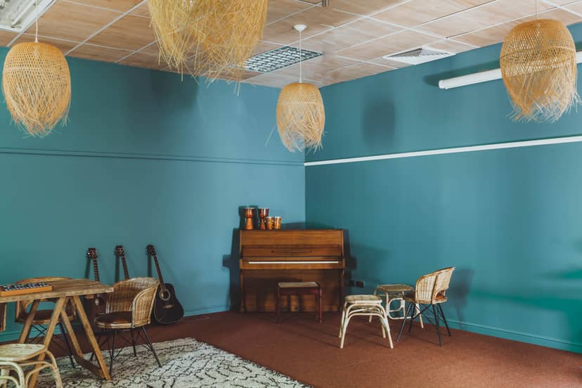 Cozy music room with teal walls, ideal for workshops and intimate gatherings.