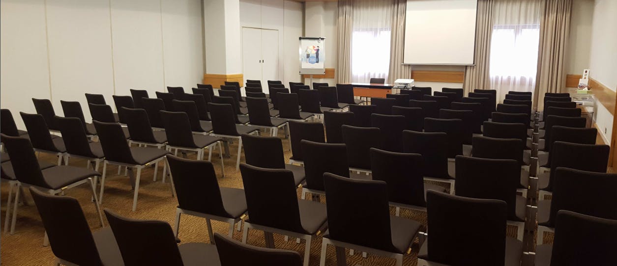 Victoria Suite meeting room at Novotel Bristol, featuring black chairs and a presentation screen.