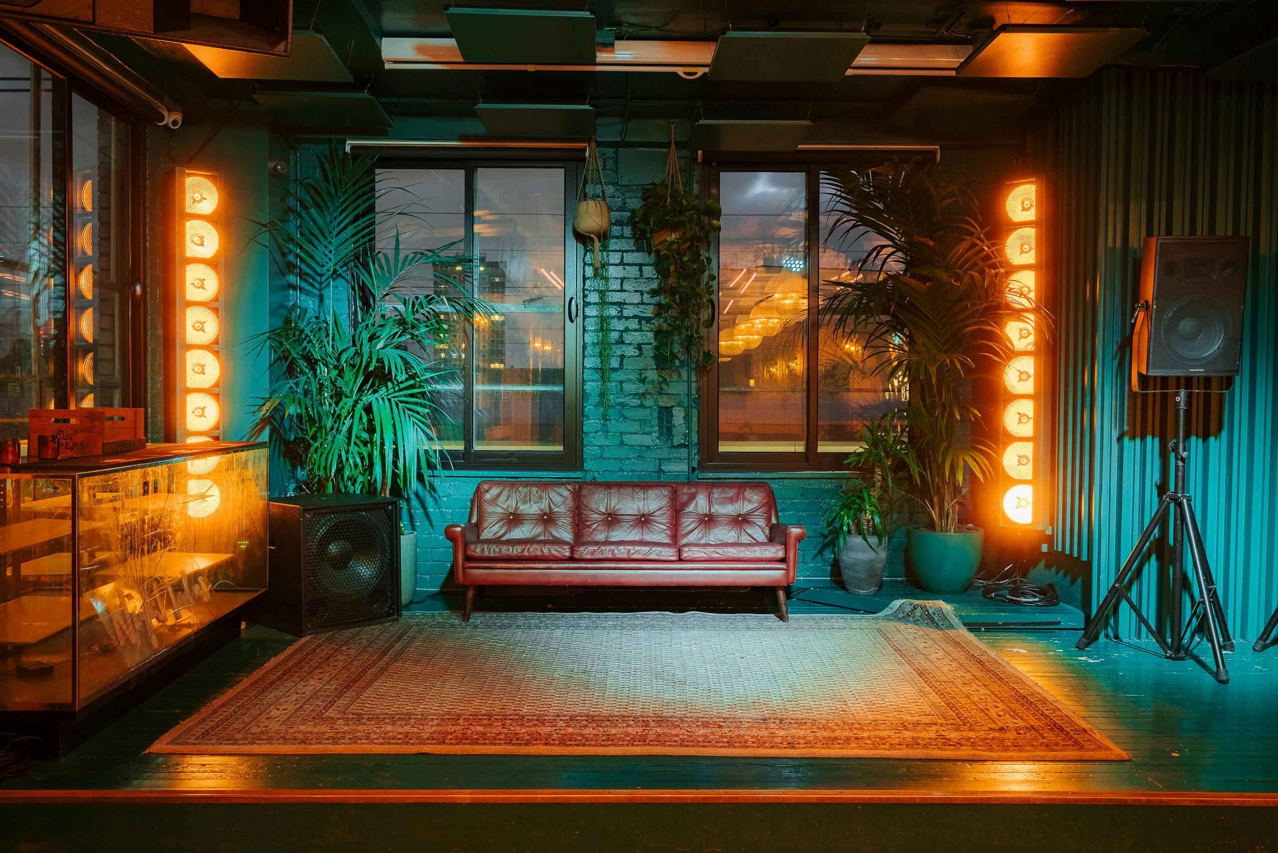 Stylish event space with red leather sofa, perfect for intimate gatherings and meetings.