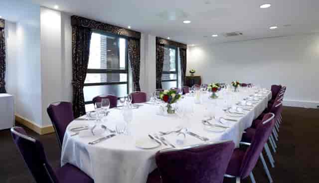 Elegant Mortimer Room dining setup with white linens and purple chairs for corporate events.