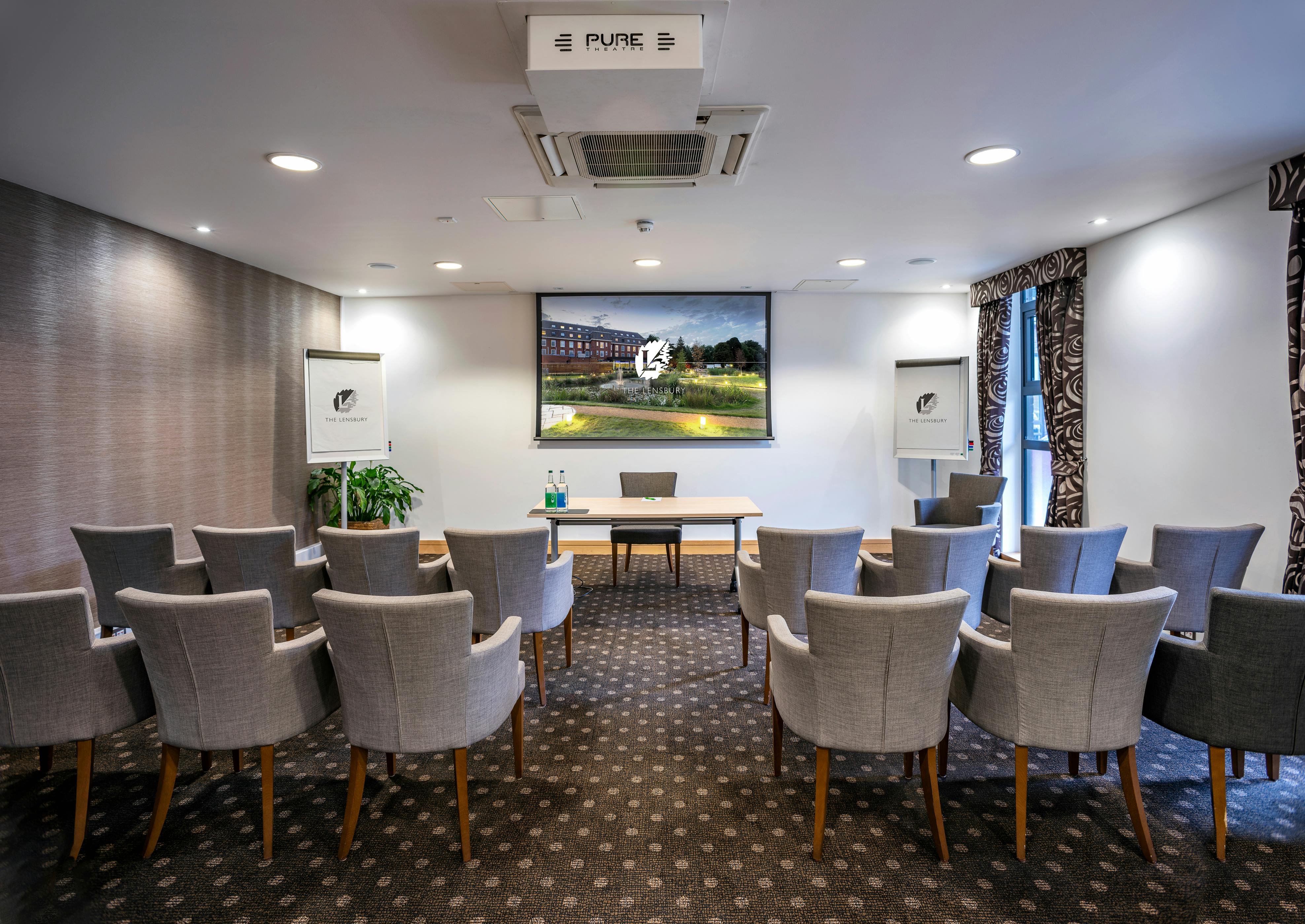 Lloyd Room at The Lensbury: professional meeting space with large screen for presentations.