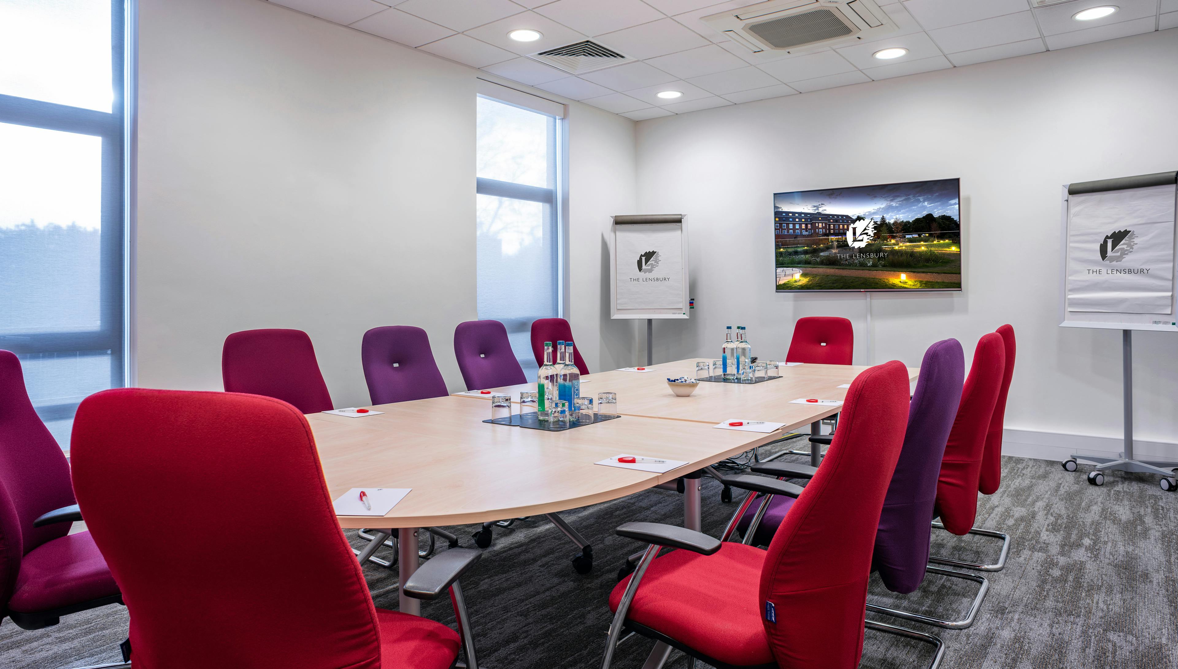 Modern Uttley Room with oval table, red chairs for meetings and presentations.