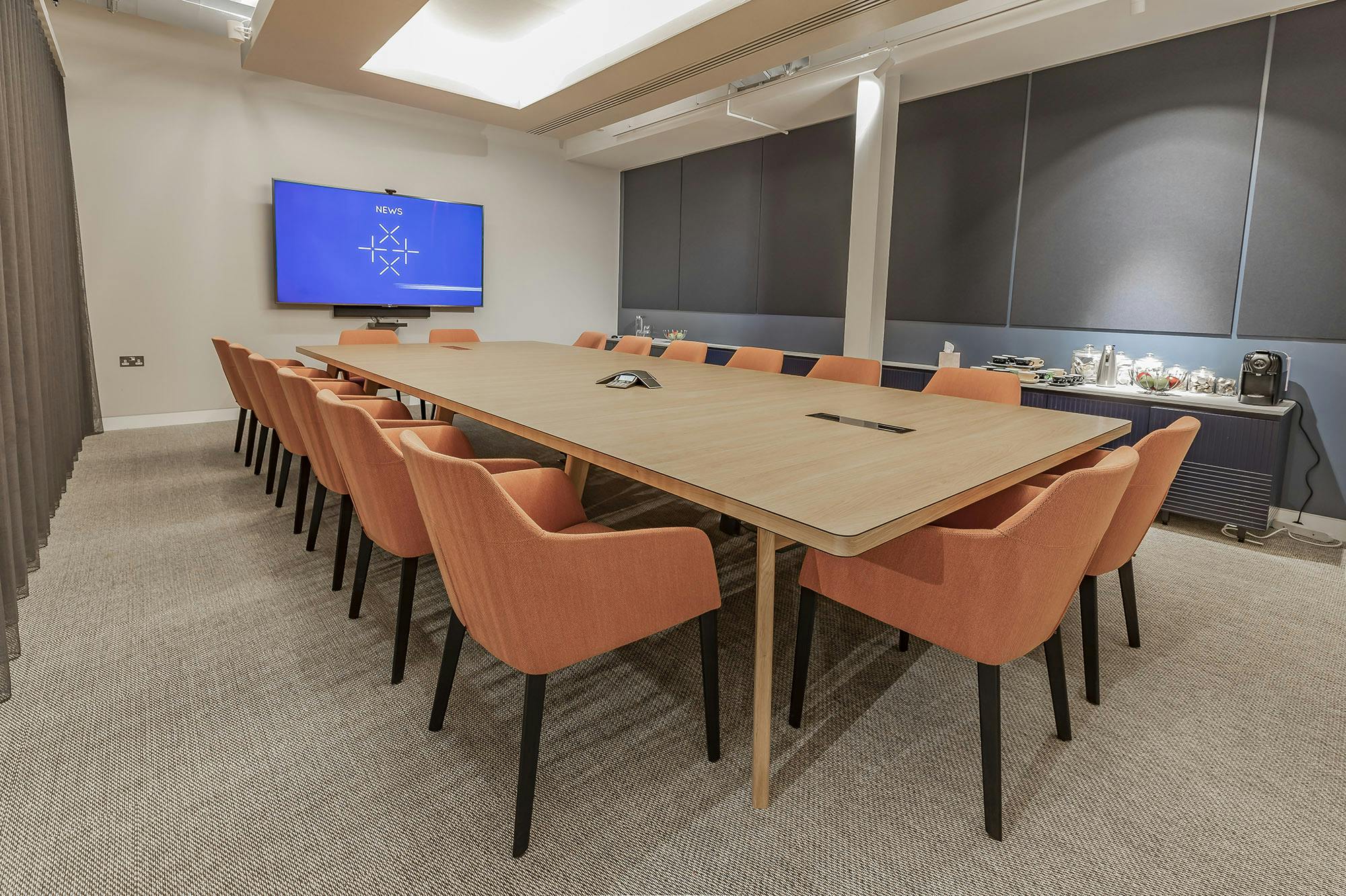 Modern conference room with wooden table and orange chairs for collaborative meetings.