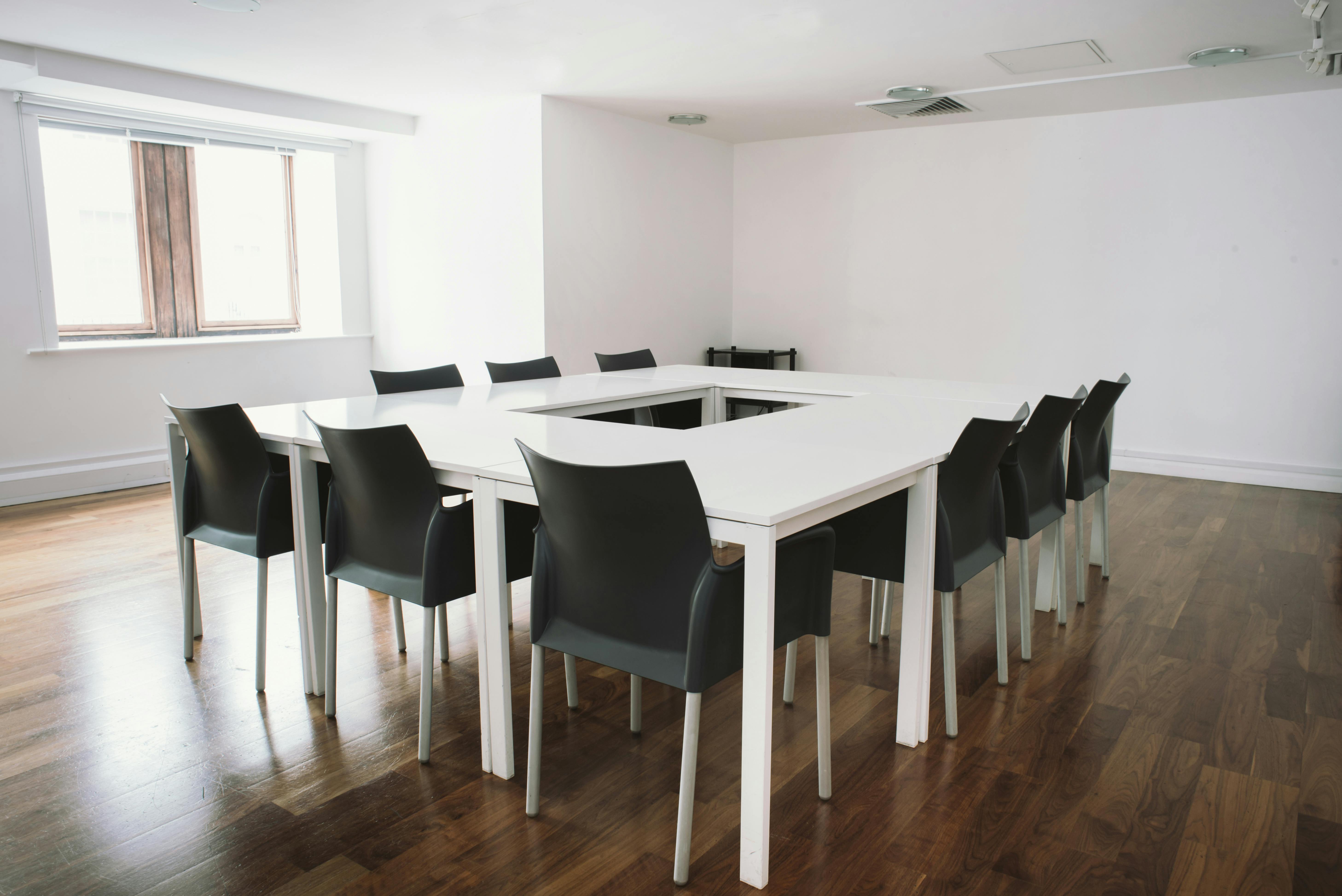 Modern conference room with square table, ideal for workshops and strategic planning.