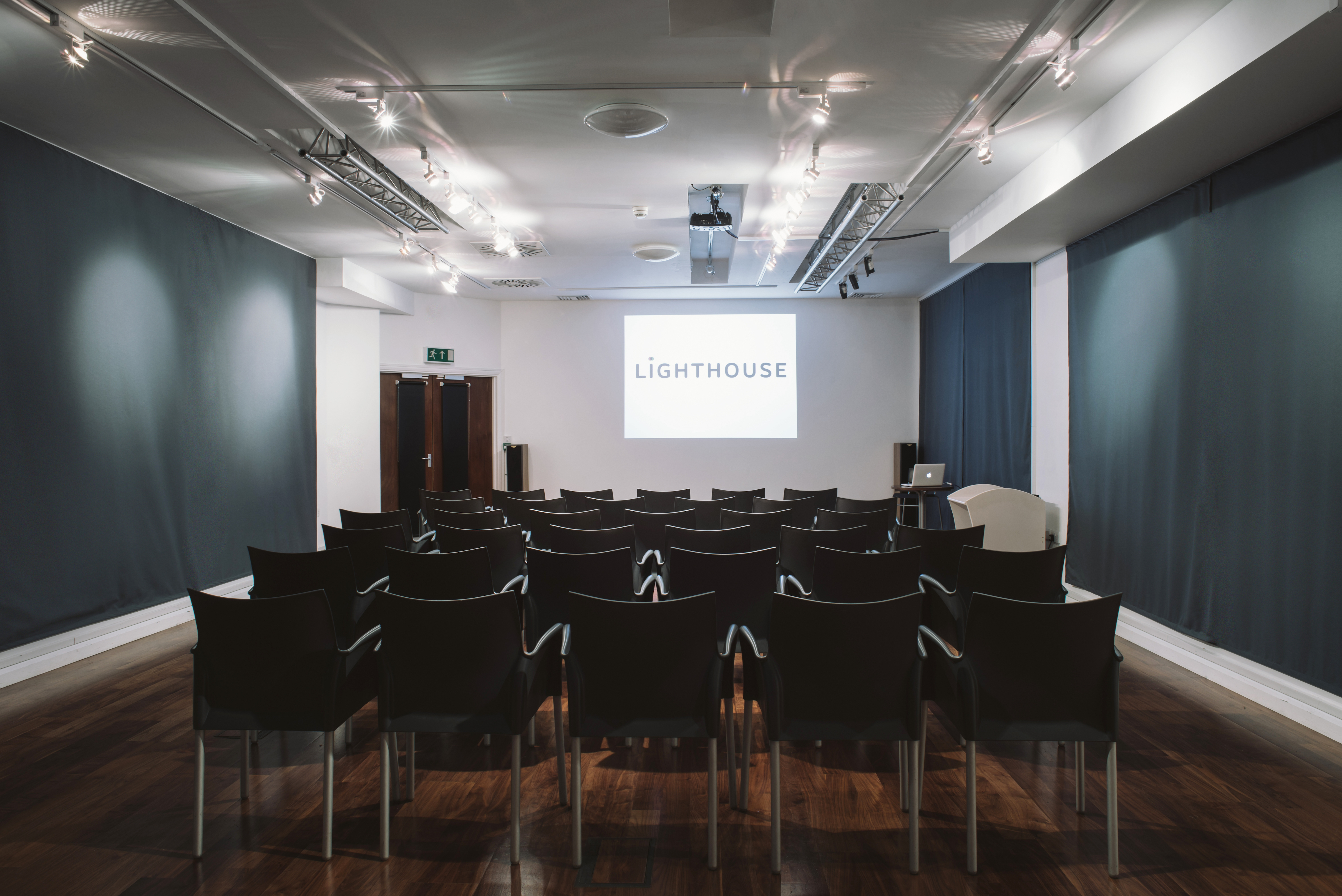 Digital Lounge meeting space with black chairs and presentation screen for corporate events.
