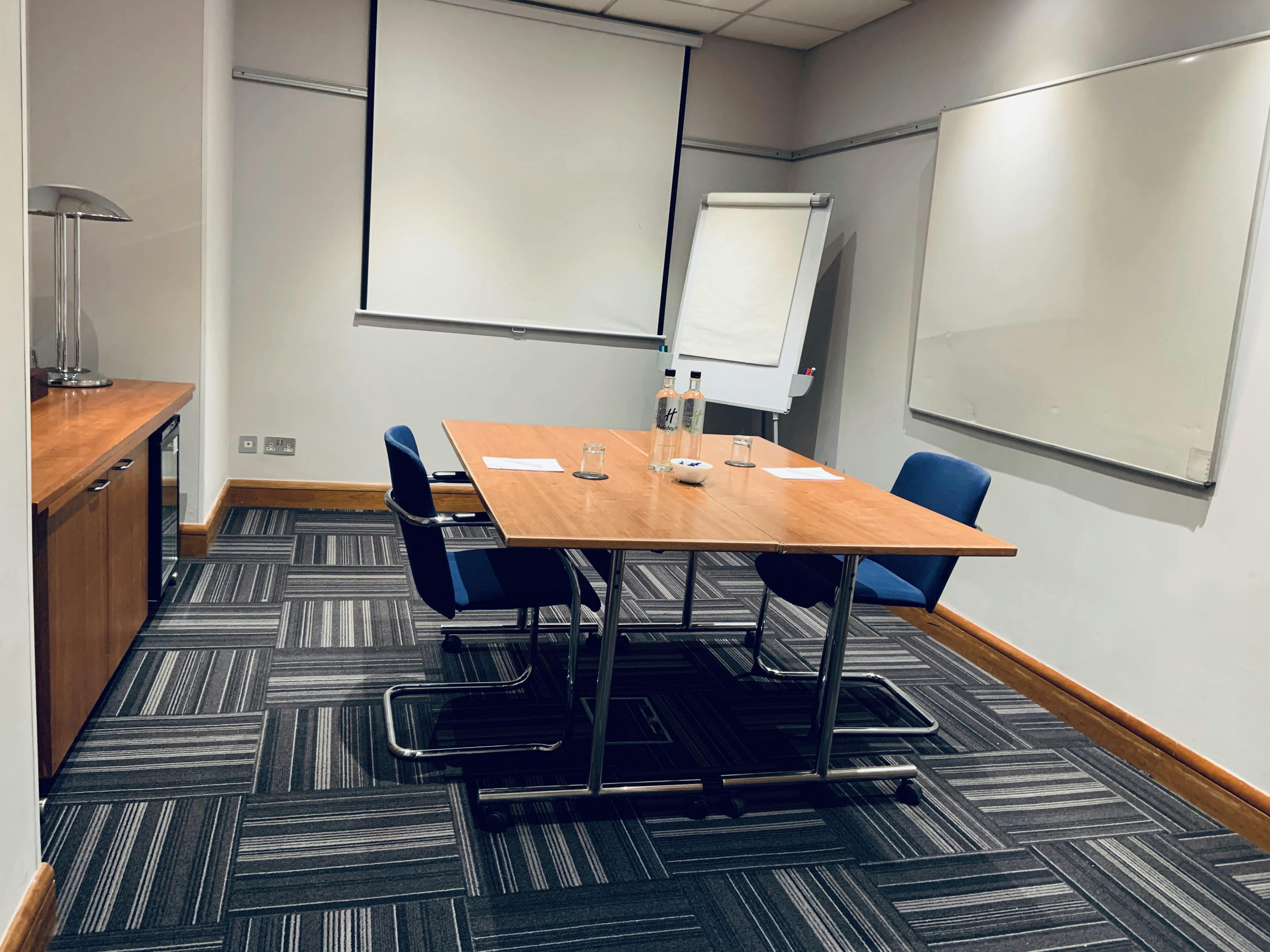 Small meeting room at Holiday Inn High Wycombe with wooden table, ideal for brainstorming sessions.