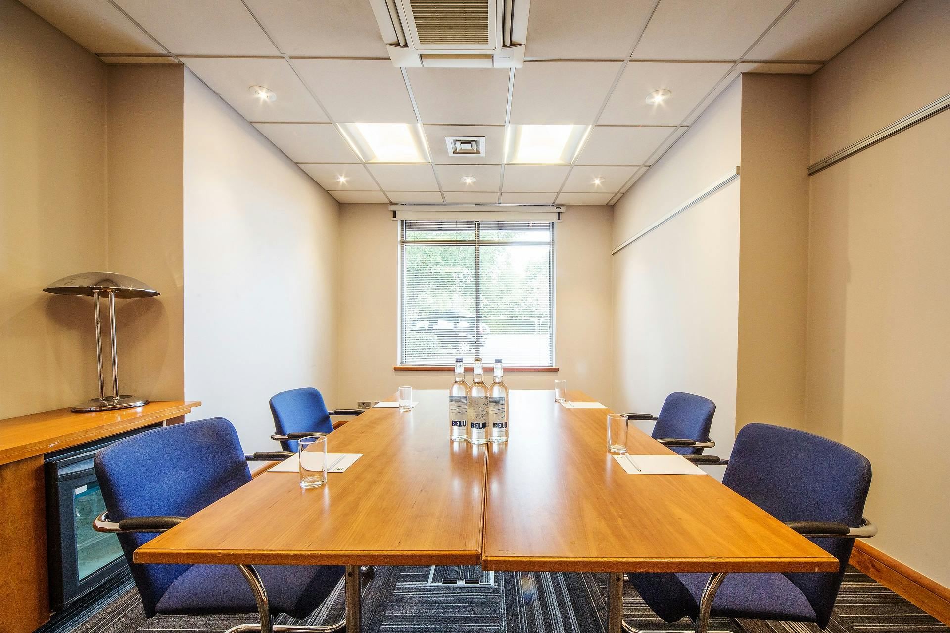 Bradenham meeting room at Holiday Inn High Wycombe, featuring a polished table and blue chairs.