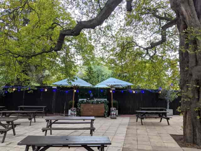 Idyllic outdoor garden venue with shaded seating for casual networking events.