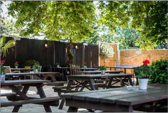 Charming outdoor garden venue with picnic tables for social gatherings and events.