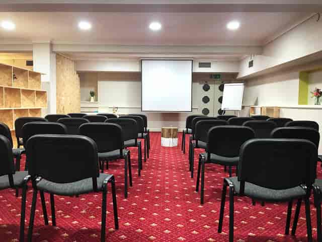 Meeting room with chairs and projection screen, ideal for workshops and conferences.